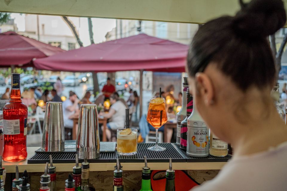 Barkeeperin an der Corso-Bar mit Blick auf die Terrasse