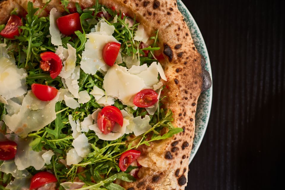 Neapolitanische Pizza mit Rucola, Parmesan und Kirschtomaten