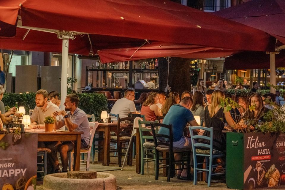 Abend auf der Terrasse des Bistro Corso unter roten Sonnenschirmen